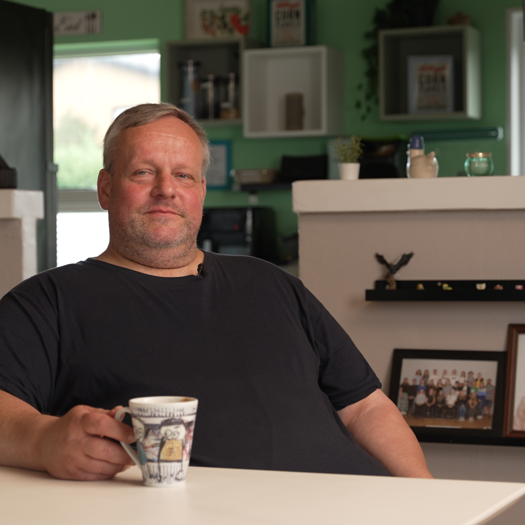 Kunde sidder i køkken med kaffekop – deler erfaring med KalkPro vandbehandler og forebyggelse af kalkaflejringer